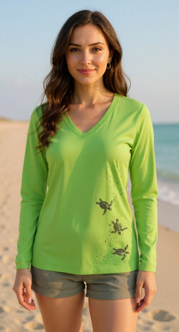 Woman in green baby turtle performance shirt by beach.